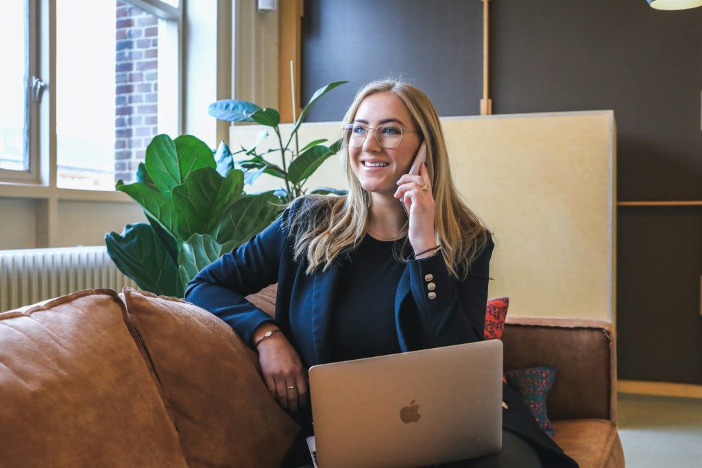 a woman sitting on a couch with a laptop and phone