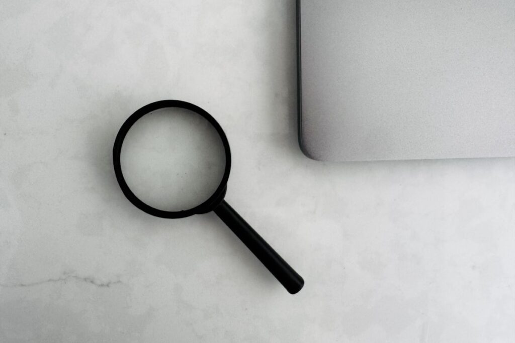 Magnifying glass beside a laptop, representing buyer due diligence