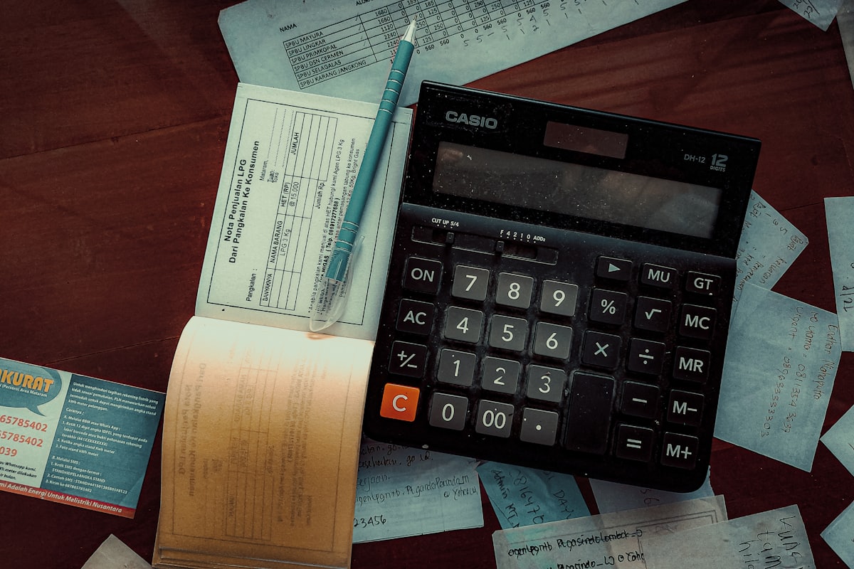 Calculator on a wooden desk beside working notes
