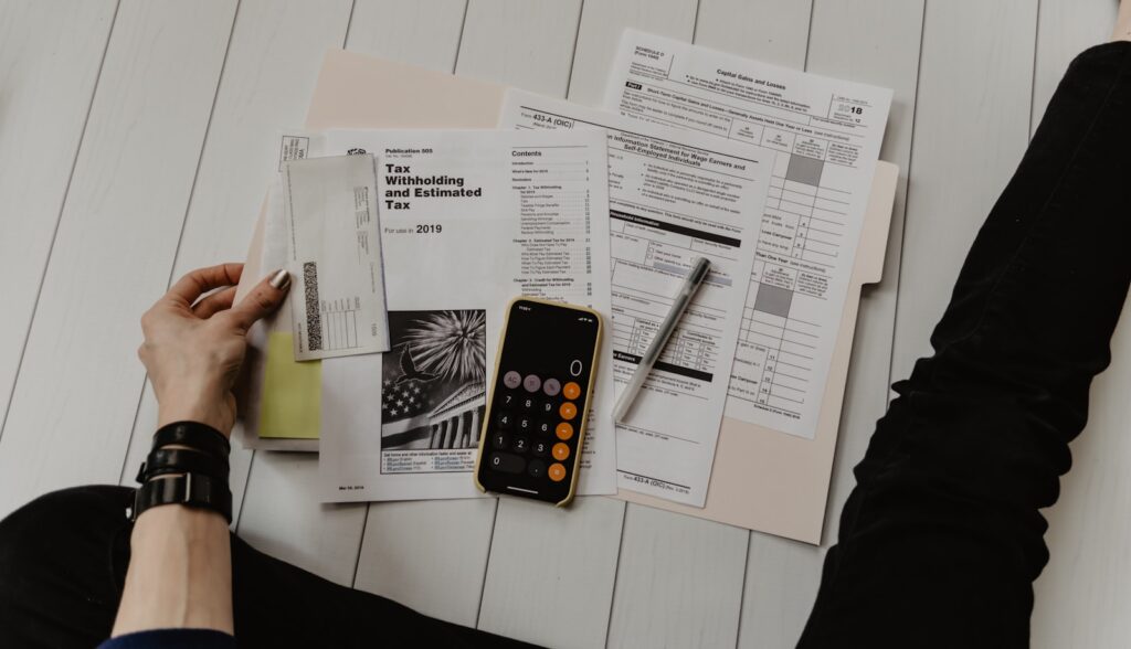 Business owner calculating net sale proceeds with a calculator and financial documents