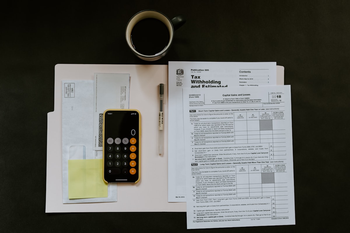 Tax paperwork, a folder and a calculator on a desk, showing why a tax return understates real business earnings