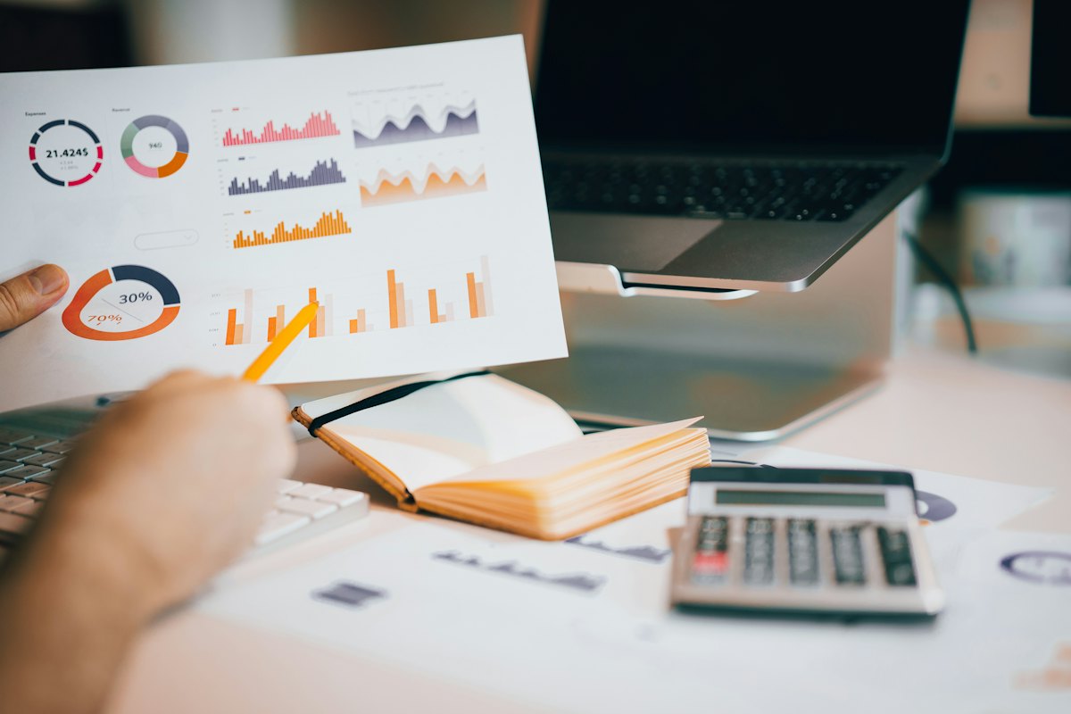 Printed charts, calculator and laptop on a desk during financial analysis