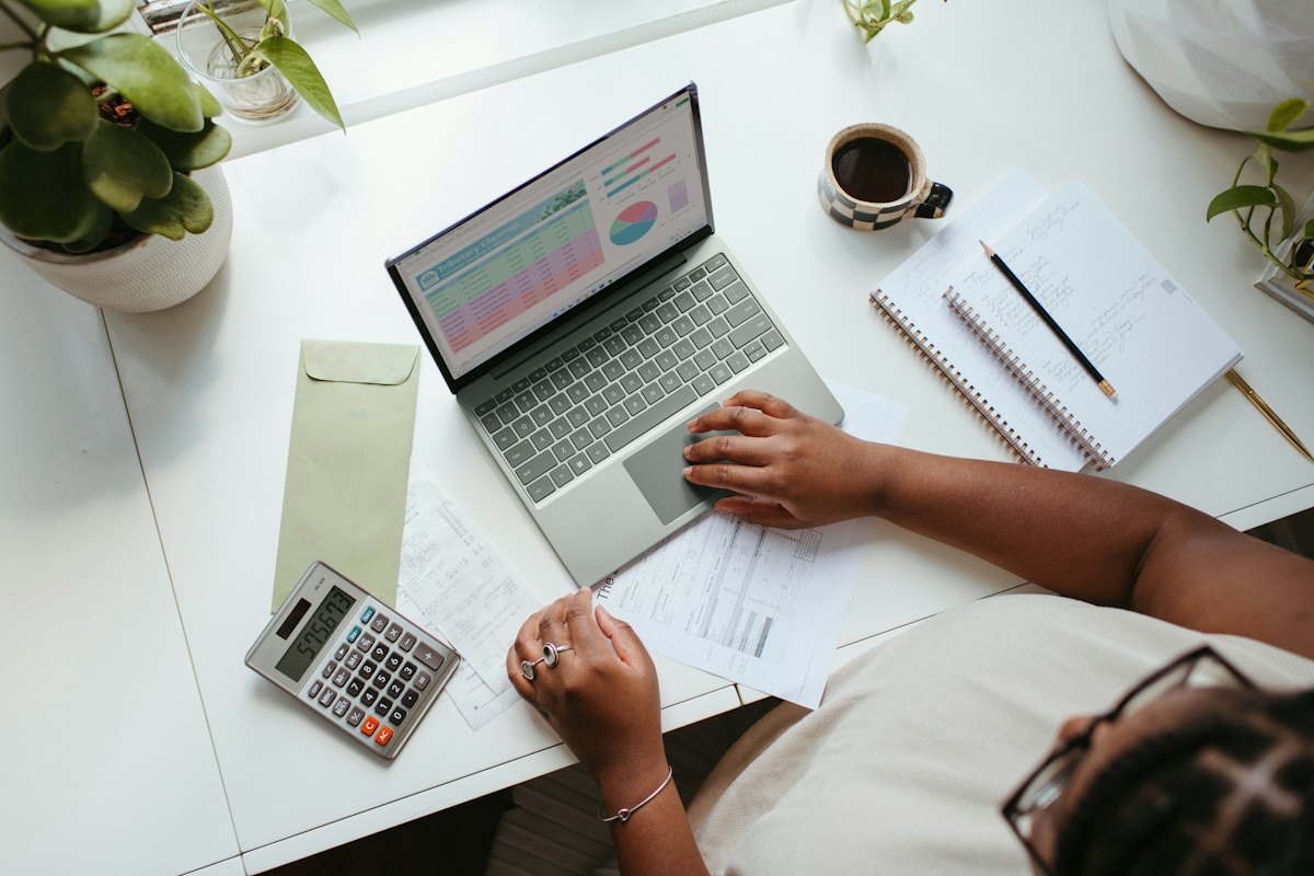 Bookkeeper reviewing financial reports on a laptop with a calculator